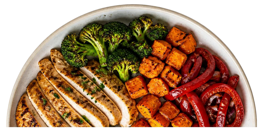 Half of a white plate filled with slices of roasted chicken breast, broccoli florets, cubed sweet potatoes, and sliced red bell peppers.