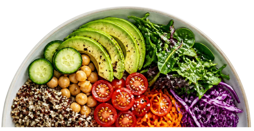 Half of a white plate filled with quinoa, chickpeas, sliced cucumbers, sliced tomatoes, shredded cabbage, and shredded carrots.